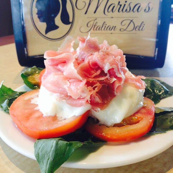 Caprese salad with sliced tomatoes, fresh mozzarella, basil, and prosciutto at Marisa's Italian Deli.